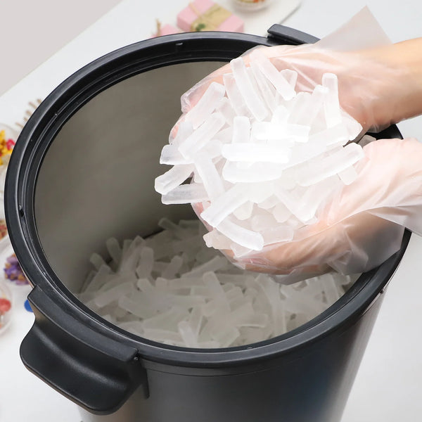 Person adding transparent candle into a black pot on a light-colored surface.